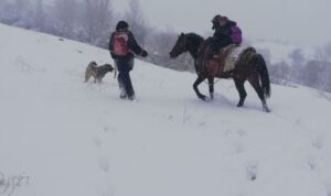 Kar yolu kapatınca, çocukları at sırtında okula götürdü